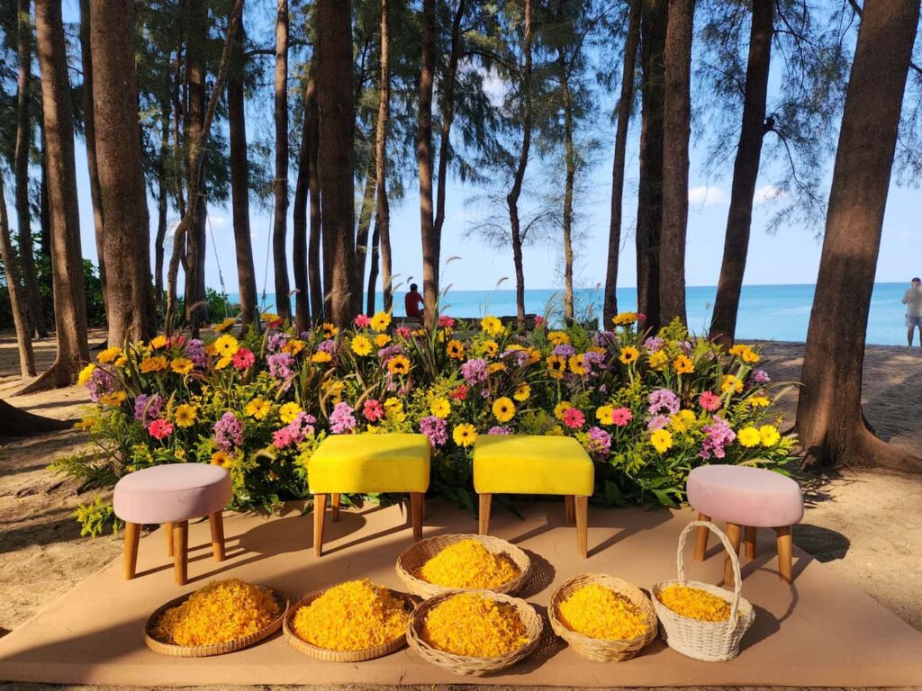 Vibrant and beautifully decorated outdoor Haldi ceremony decoration station, featuring colorful flowers, stools, and traditional elements